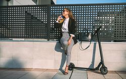 Businesswoman with mobile and her scooter next