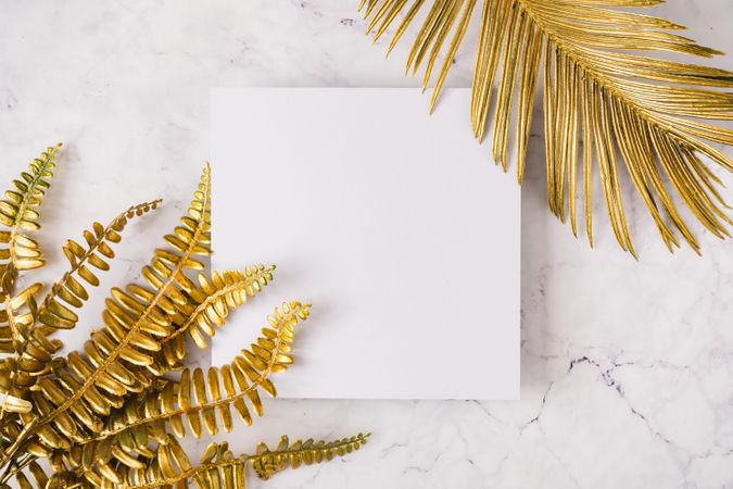 Gold leaves on corner of square paper on marble background