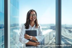 Happy business investor standing in office in a high-rise building overlooking the cityscape 436NX5