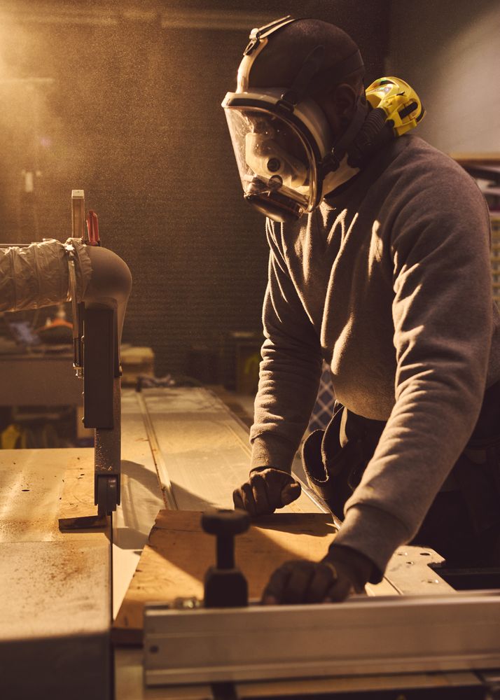 Man in protective face mask cutting wood