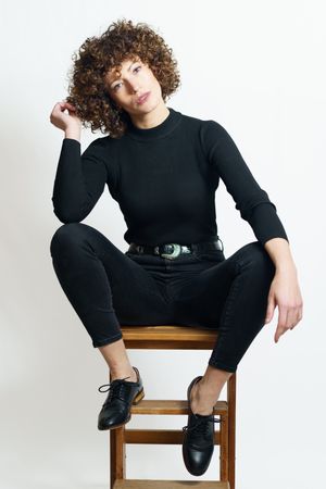 Stylish woman in dark outfit sitting on wooden bench