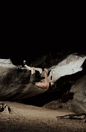 Man practicing rock climbing among large rocks in a forest