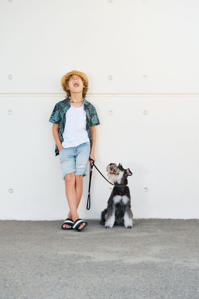 Stylish boy screaming with dog on sidewalk