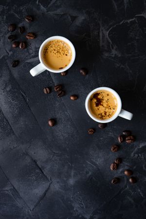 Top view of two espressos on table with scattered beans