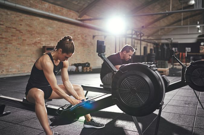 Crossfit couple adjusting rowing machine for workout