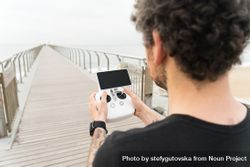 Rearview man with remote for drone on wooden boardwalk on beach 4ORR75