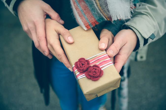 Four hands holding a giftbox