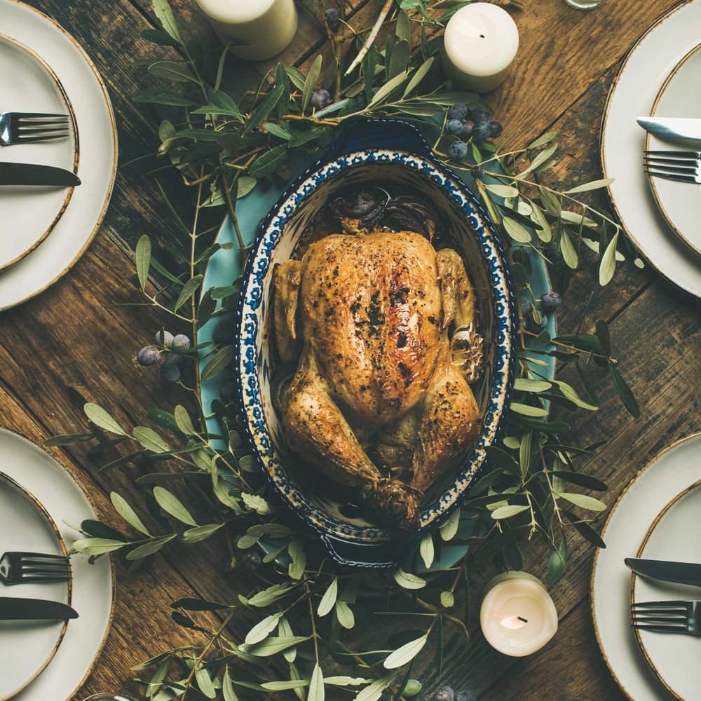 Centerpiece of roast chicken with decorative branches, with four plate settings, square crop