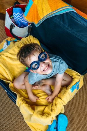 Funny boy smiling sitting inside a suitcase