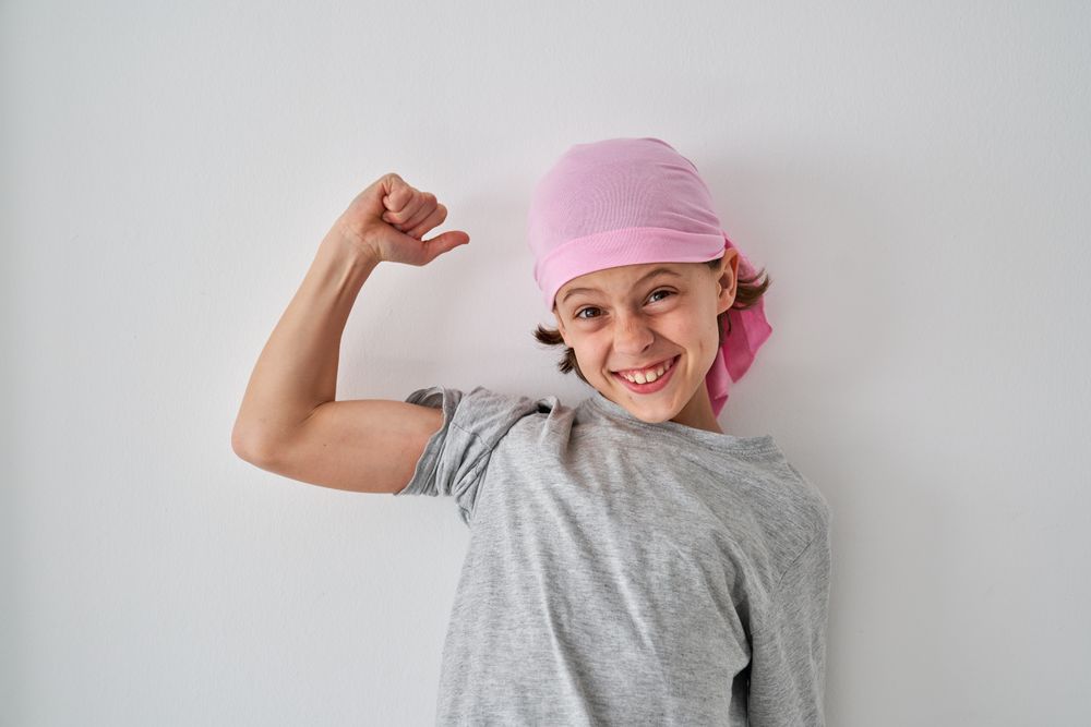 Joyful little boy smiling brightly and showing bicep