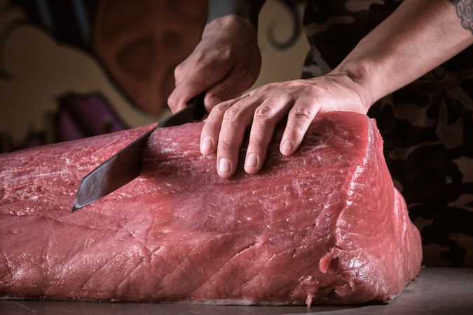 Male hands of a chef cutting a delicious loin of fresh bluefin t