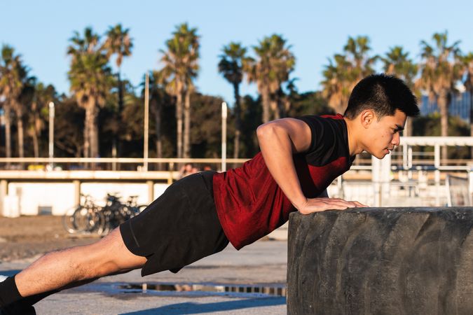 Athletic man doing push ups against tire