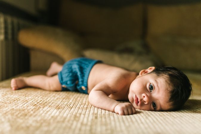 innocent newborn baby in back lying on sofa at home