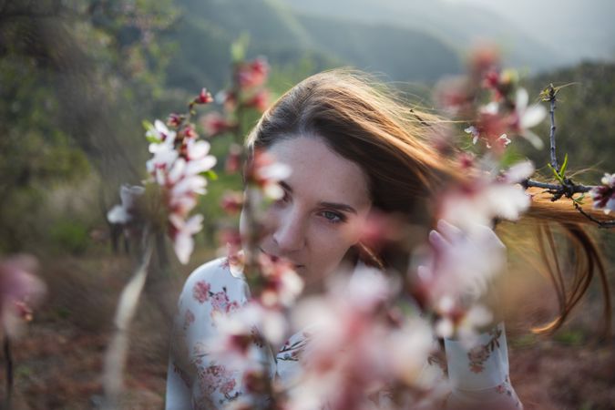 Young happy woman between trees in garden