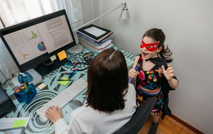 Woman working from home with her daughter interrupting her