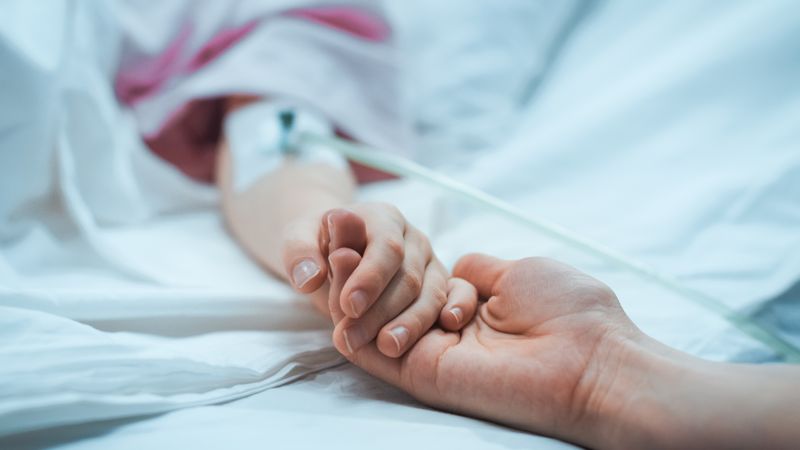 Recovering Little Child Lying in the Hospital Bed Sleeping, Mother Holds Her Hand Comforting.