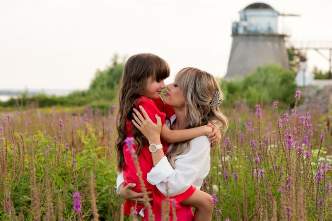 Mom and little daughter walking among meadow flowers
