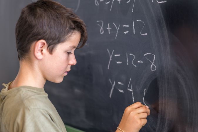 Teenage boy solving equation at chalk board
