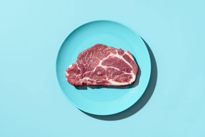 Raw pork steak on a plate, top view