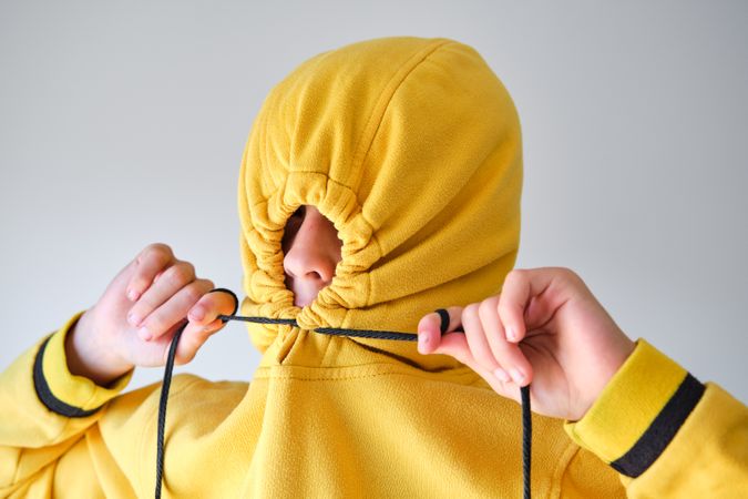 Anonymous child tightening drawstrings on hood