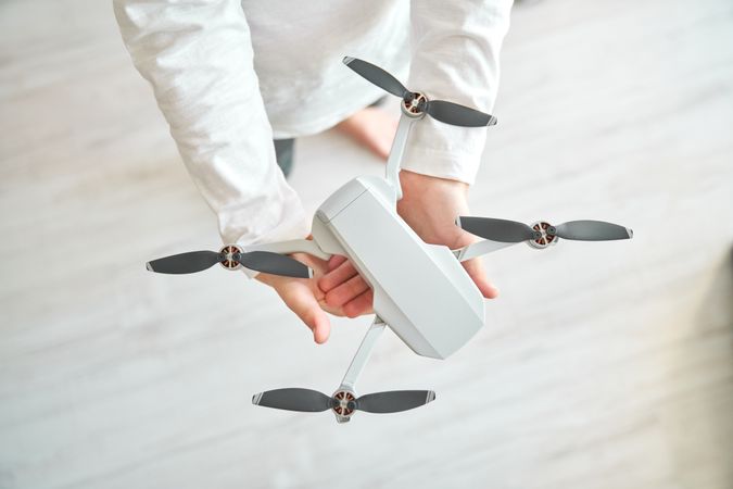 Crop preteen boy with unmanned drone preparing for flying