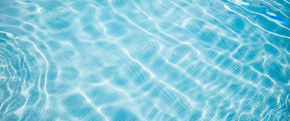 Wide shot of clear pool water with ripples wide