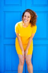 Happy woman leaning forward in front of blue door