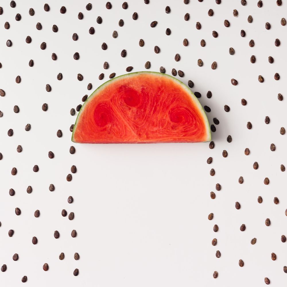 Watermelon slice surrounded with seeds raining