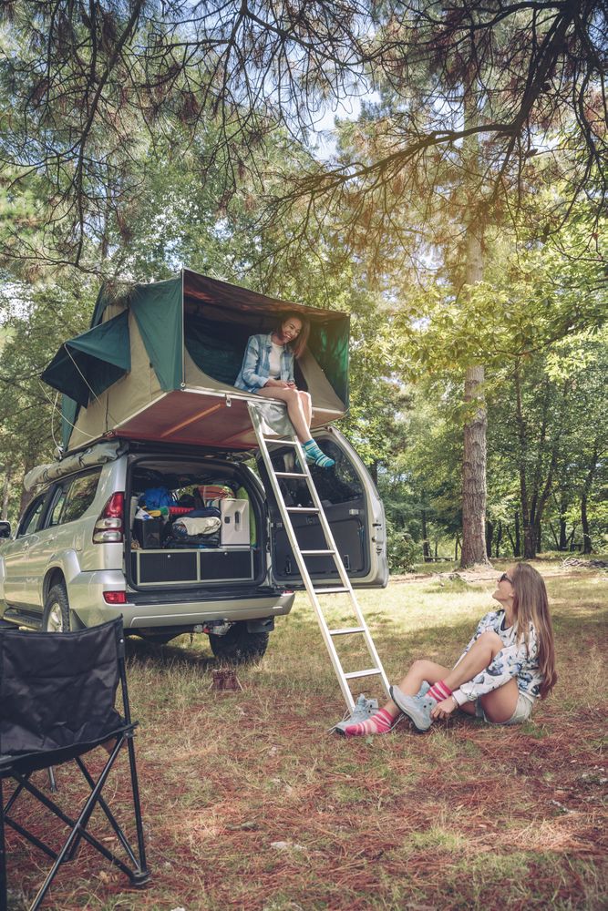 Woman in tent over car getting ready for hike in forest