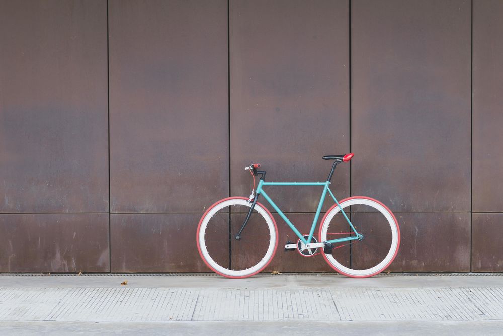 Red and green bicycle parked against a brown wall