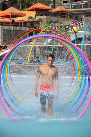 Man in swimsuit shorts standing in water fountain