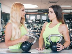 Female athletes with kettlebells looking at each other