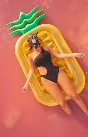 Woman lying on air mattress in pink lake water
