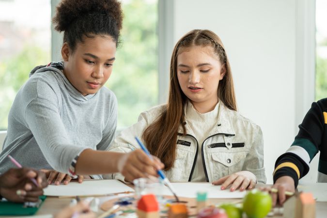 Children using paintbrush to sketch on paper