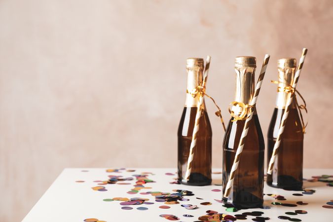 Mini champagne bottles with straws on decorated background, copy space