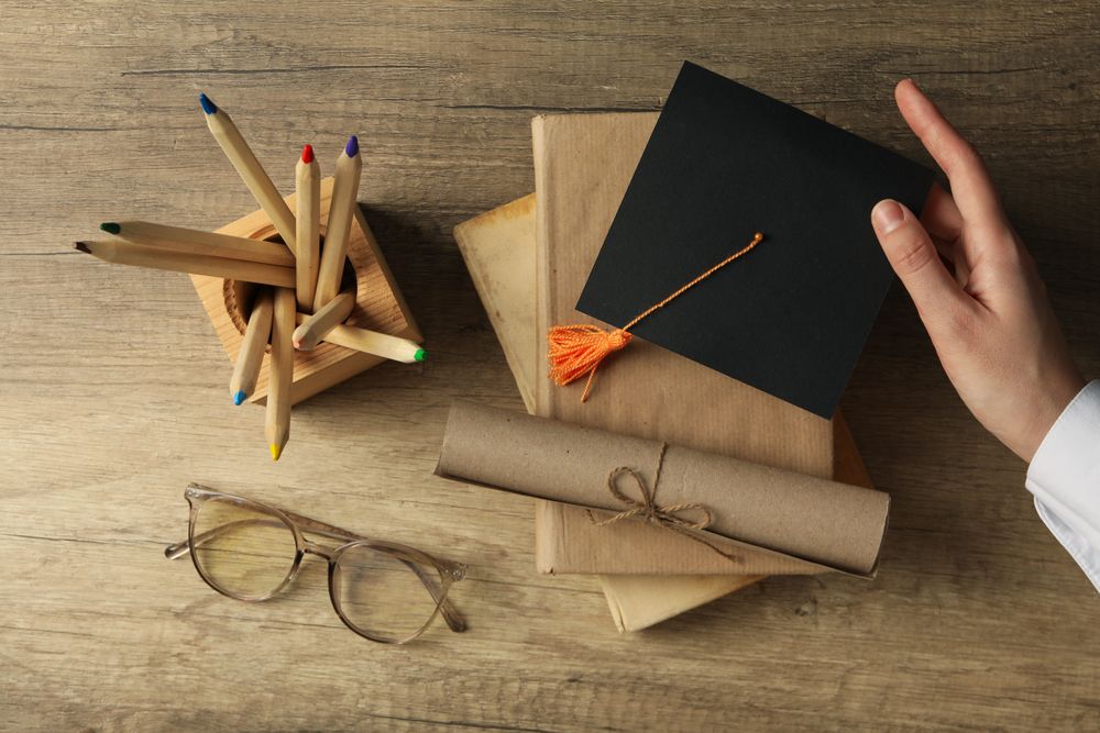Graduate hat and books on wooden table