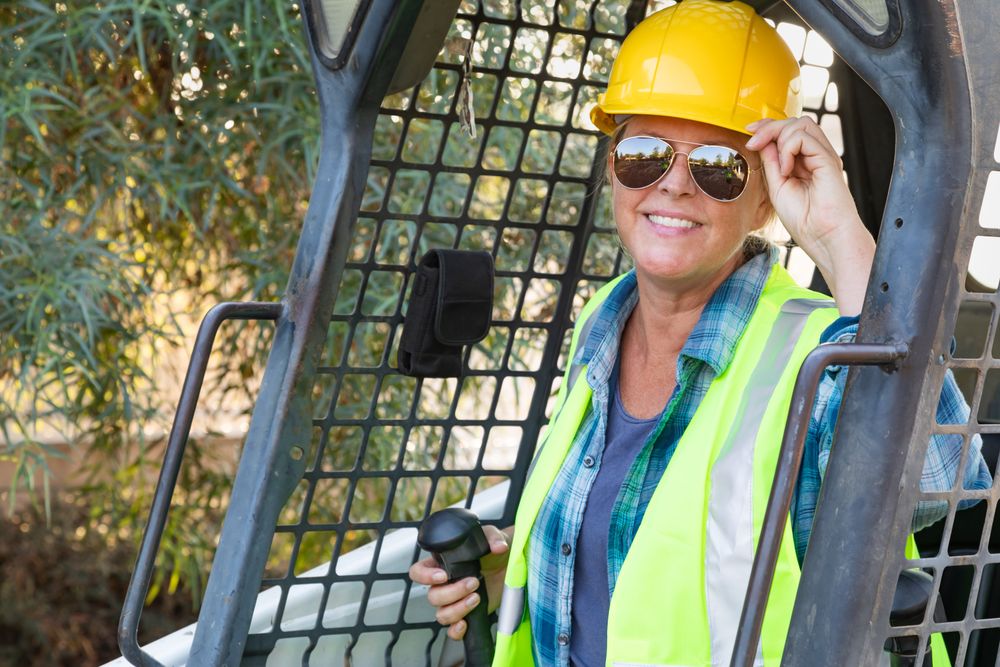 Smiling Female Worker Using Small Bulldozer At Constrcution Site