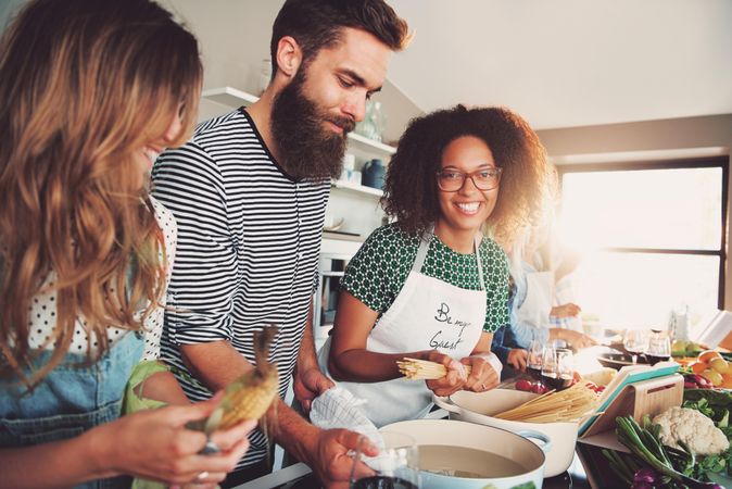 Black woman smiling in the kitchen with her friends as she boils pasta
