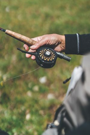Man carrying fishing rod and standing at meadow