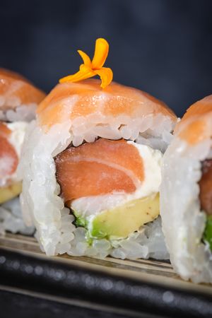 Sushi rolls covered with fresh salmon served on plate