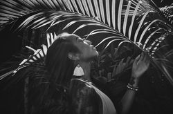 Woman with head to the sun rays under palm leaf