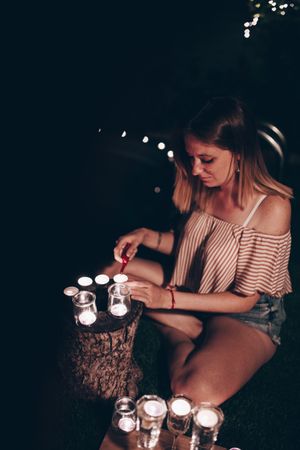 Woman lighting candles in dark garden