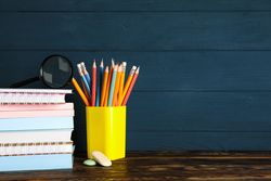 Composition with school supplies on wood table against dark background