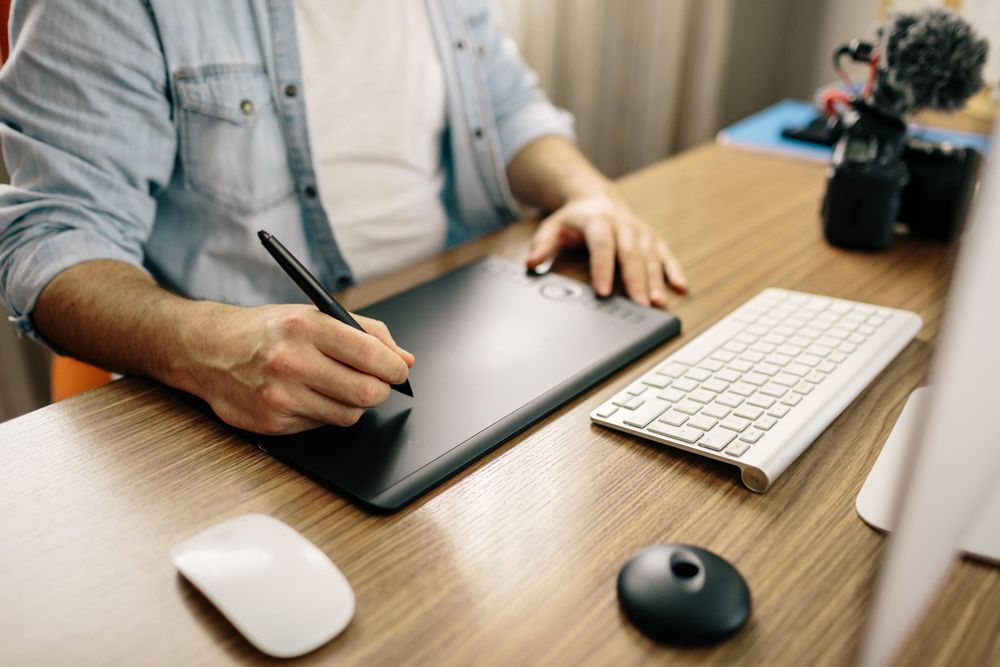 Man drawing on tablet sitting at a desk
