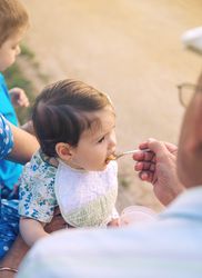 Man feeding baby girl sitting outside