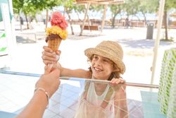 Smiling kid taking ice cream from hand of seller