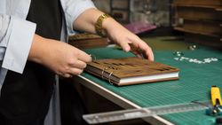Female hands hold notebook with removable blocks and wooden cover together in workshop