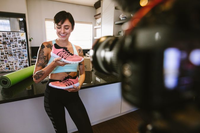 Woman social media influencer explaining the benefits of a new sports shoe filming herself at home