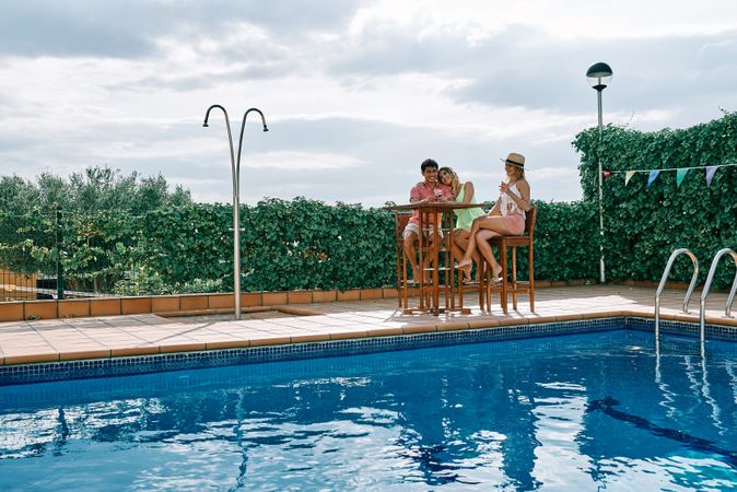 a group of young people having a celebration by the pool on a cloudy summer day