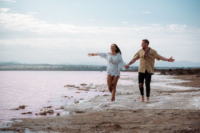 adorable couple walking on an amazing beach with pink water